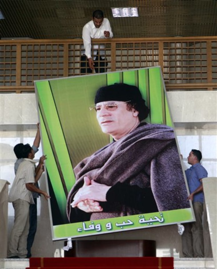 FILE - In this Oct. 8, 2010 file photo, Libyan workers hang a giant poster showing Libyan leader Moammar Gadhafi at the  media center in Sirte, Libya, where Libya hosts one-day Arab League summit. It stands as a daunting barrier to Libya's rebels: Moammar Gadhafi's hometown of Sirte. Effectively Libya's second capital, the city is under lockdown, dominated by heavily armed fighters from Gadhafi's tribe, its entrances reportedly mined to prevent any opposition attack. Taking the Mediterranean coastal city, about 130 miles (210 kilometers) west of the nearest rebel position, could prove tough. Gadhafi's tribe is the most powerful in the city of some 150,000. Additionally, the city is guarded by an elite unit led by one of the Libyan leader's sons.(AP Photo/Amr Nabil, File)